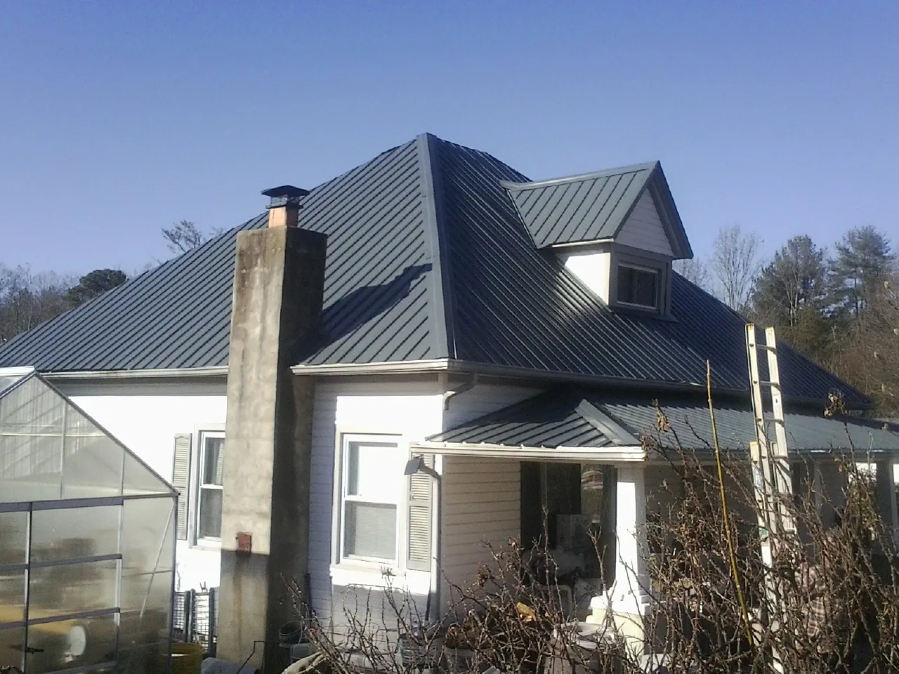 Dark blue standing seam metal roof on a white farmhouse with dormer — Slate & Tile Roof Repair by Roofing Brothers in Chilo