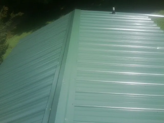New green metal panels meeting at the ridge of a roof — Flat Roof Repair work by our crew in Chilo