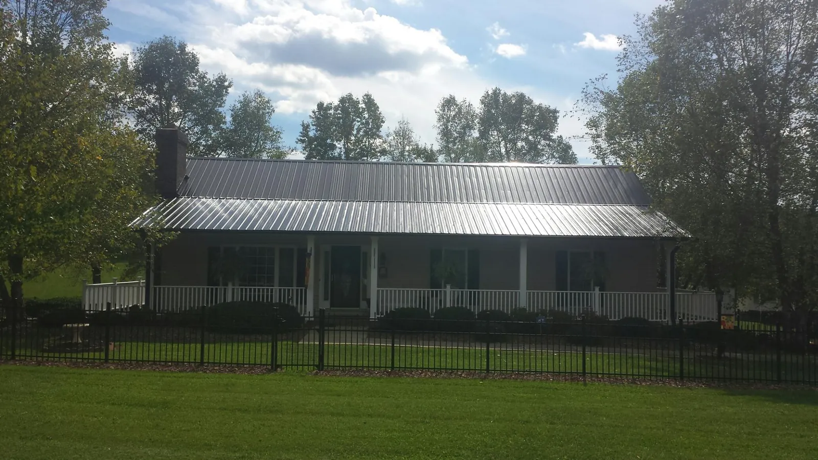 Gray metal roof on a brick ranch with a full width front porch — Gutter Guard Installation work by our crew in Chilo
